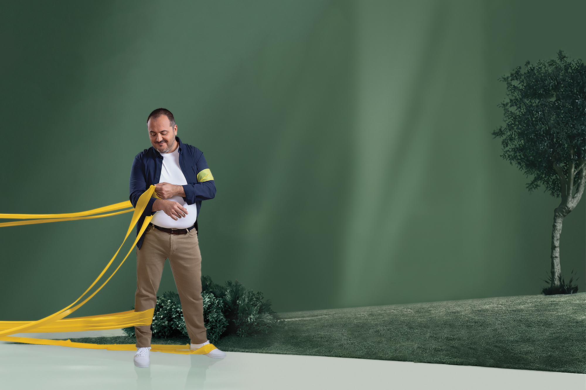 Um homem com obesidade, num parque, a remover as faixas de resistência dos seus braços, enquanto continua a ter as faixas à volta das pernas.
